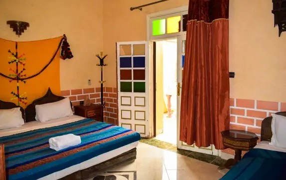 Triple room with colourful Moroccan bedding at Riad Lghiam in Rissani